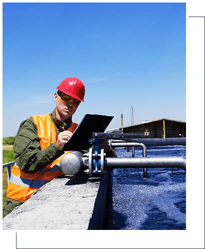 A man in an orange hard hat is working on his laptop.